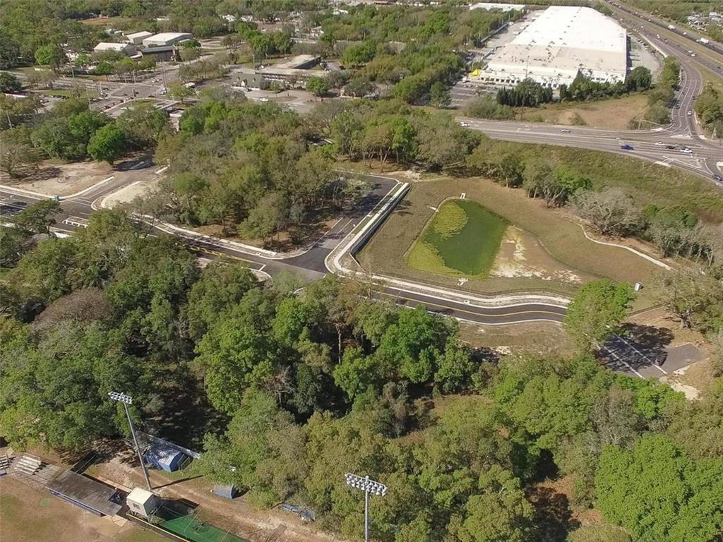 An aerial view shows a paved road, a retention pond, and surrounding wooded areas — 6011 COUNTY ROAD 579, SEFFNER, FL