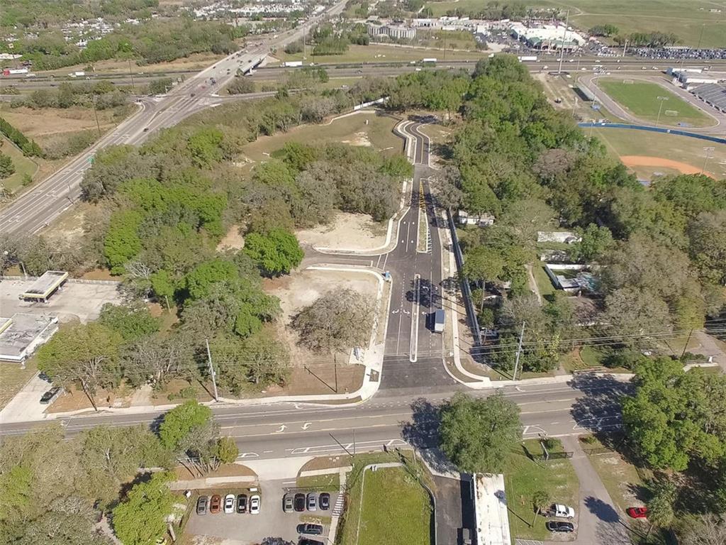 An aerial view shows a newly paved road extending into a wooded, undeveloped lot — 6011 COUNTY ROAD 579, SEFFNER, FL