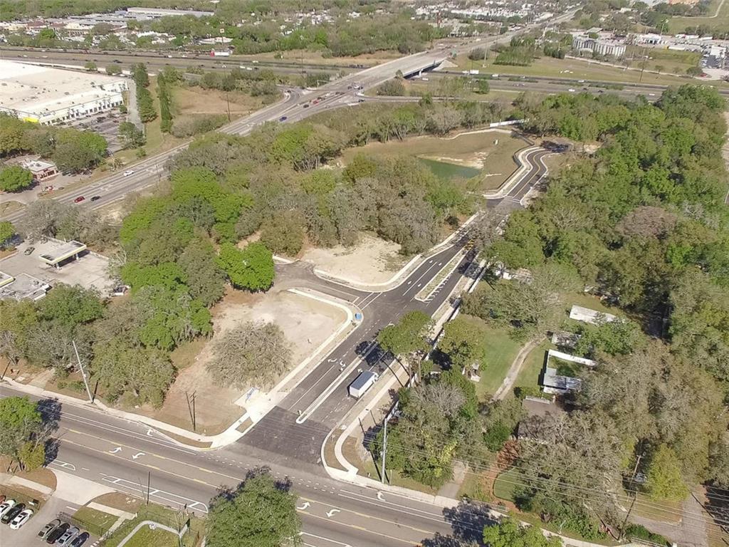 An aerial view shows a newly paved road intersection surrounded by wooded land and infrastructure — 6011 COUNTY ROAD 579, SEFFNER, FL