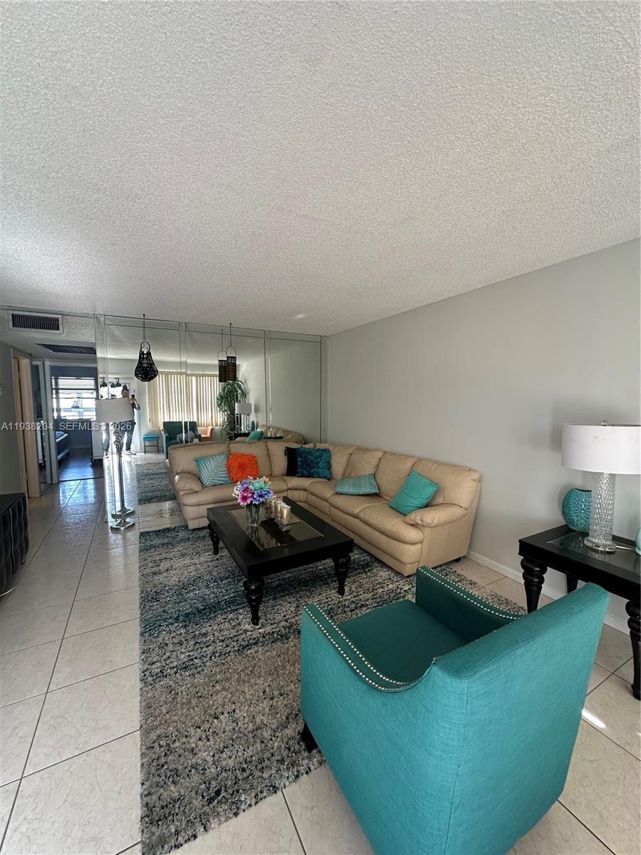 A living room features a beige sectional sofa, a teal armchair, and a mirrored wall — 3043 Exeter, Boca Raton FL 33434, BOCA RATON, FL