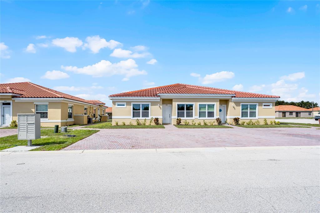 A beige duplex with a red tile roof and a brick paver driveway — 1824 CORIANDER DRIVE, KISSIMMEE, FL