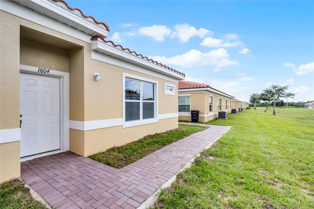 A tan exterior of a single-story home with a brick walkway and tiled roof — 1824 CORIANDER DRIVE, KISSIMMEE, FL