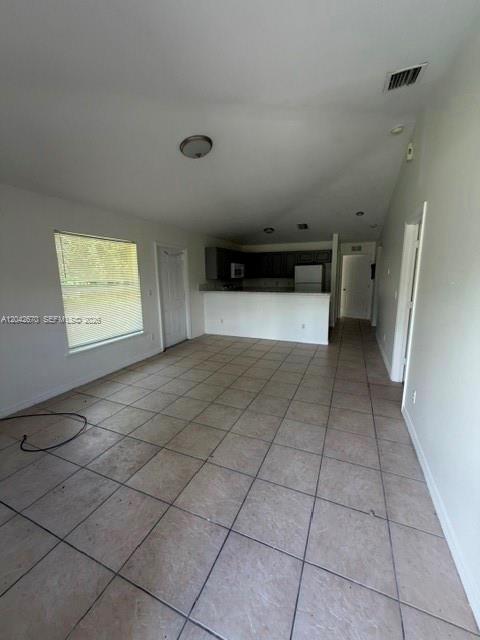 An open-concept living area with tile flooring leads to a kitchen with dark cabinetry — 625 Meadow # 625, Lehigh Acres FL 33973, LEHIGH ACRES, FL