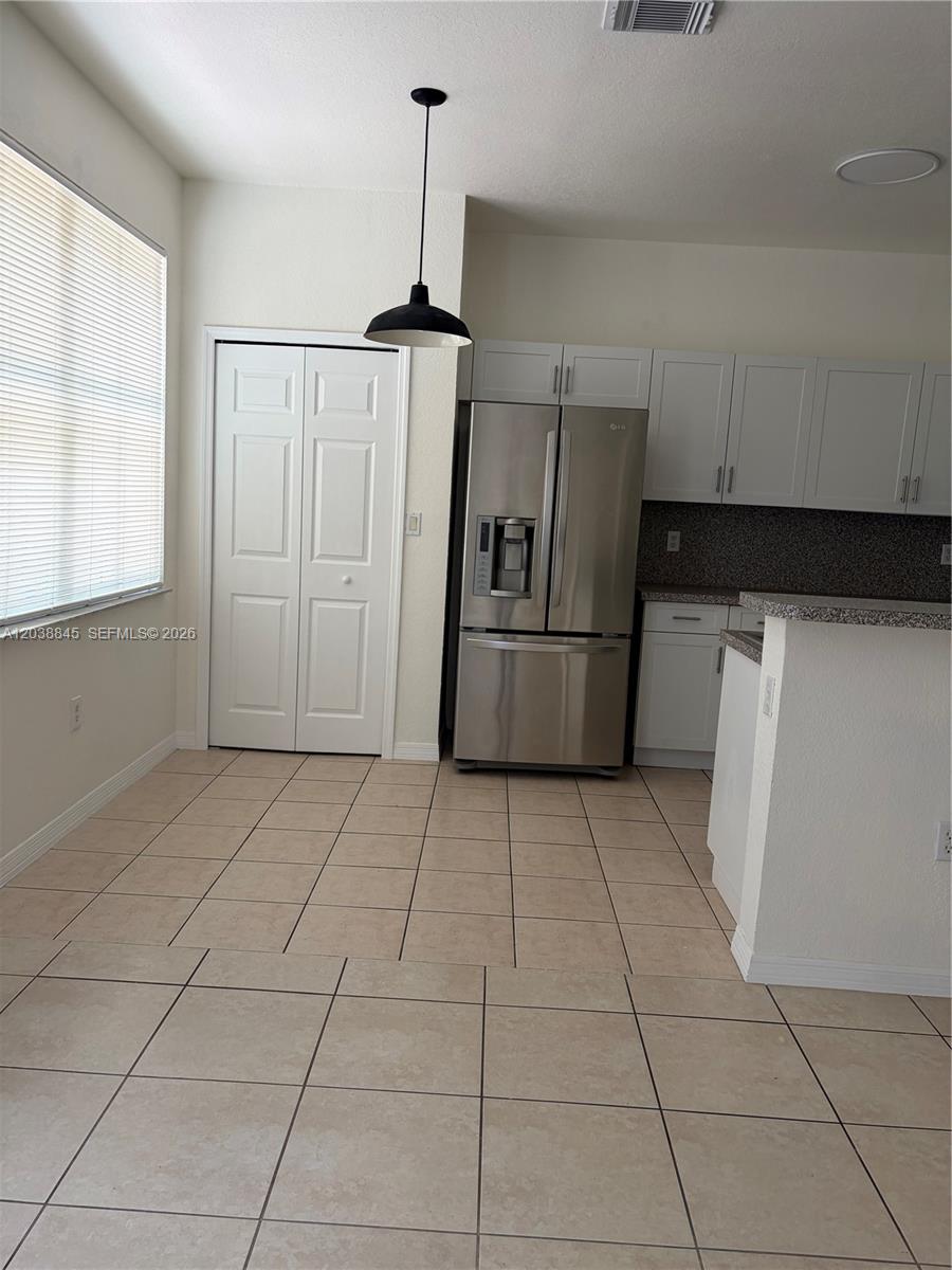 A kitchen features white cabinets, stainless steel appliances, and beige tile flooring — 12393 SW 124th Ter, Miami FL 33186, MIAMI, FL