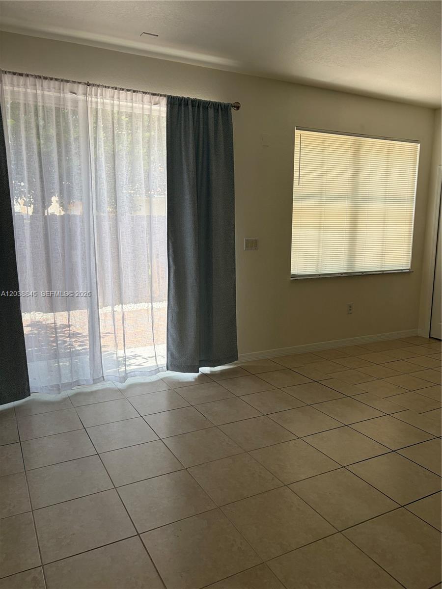 A room with beige tile flooring, a sliding glass door, and a window with blinds — 12393 SW 124th Ter, Miami FL 33186, MIAMI, FL