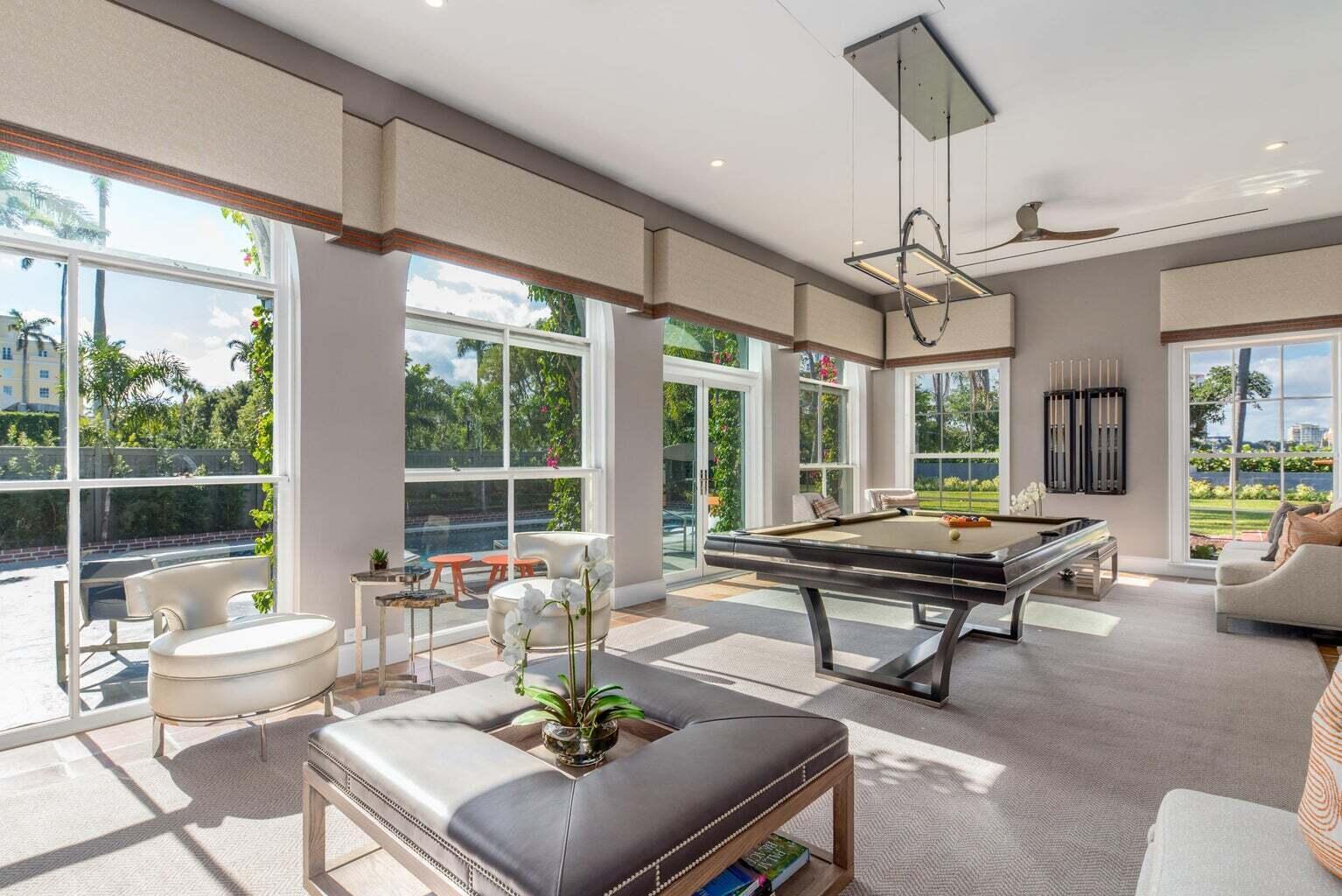 A bright game room features a pool table, lounge seating, and large windows overlooking a pool — 15 S Lake Trail, Palm Beach FL 33480, PALM BEACH, FL