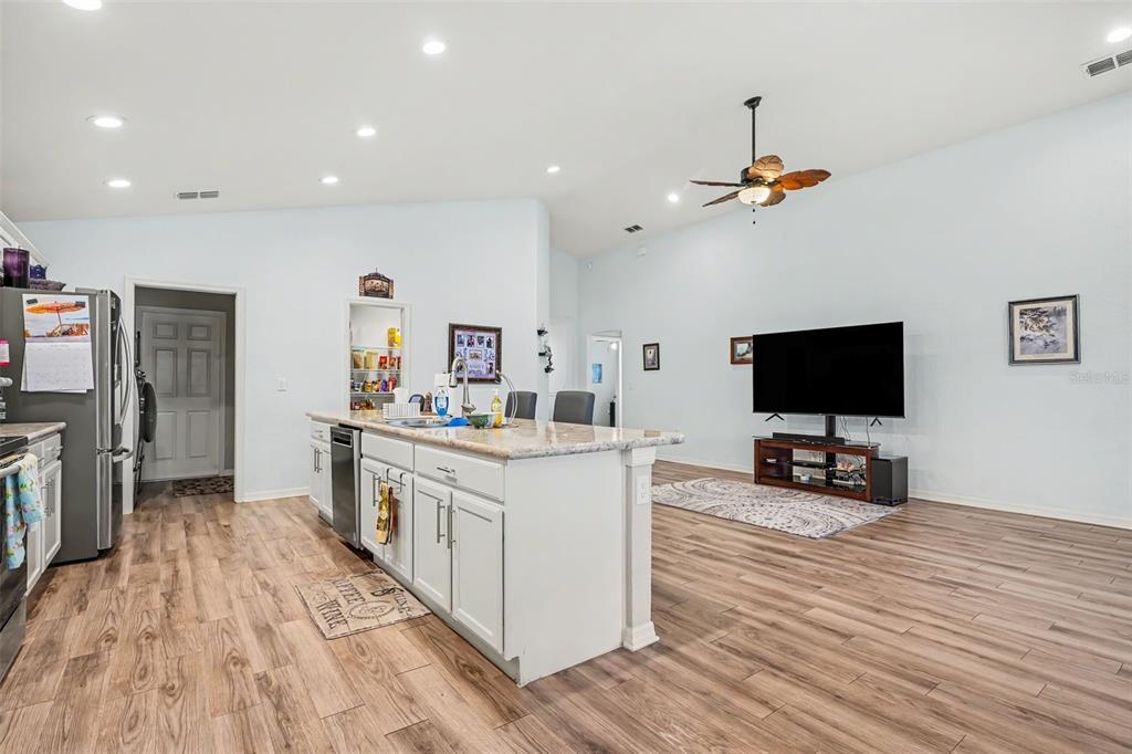 A kitchen features white cabinets, granite countertops, a blue mosaic backsplash, and stainless steel appliances — 3913 WHITE IBIS RD, LAKELAND, FL