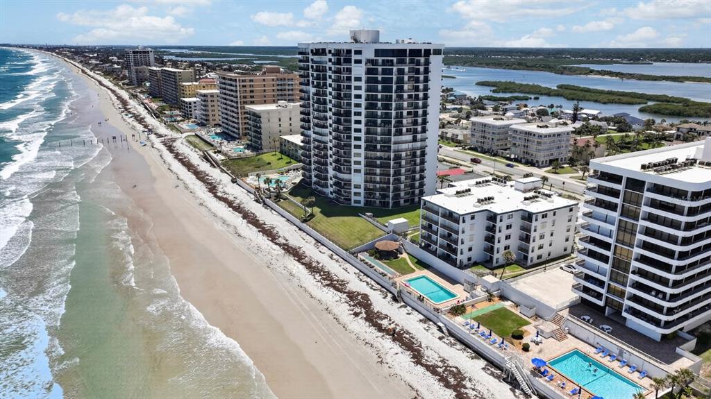 An aerial view shows several high-rise beachfront condominiums along a sandy coastline — 3747 S ATLANTIC AVENUE UNIT 2020, DAYTONA BEACH, FL