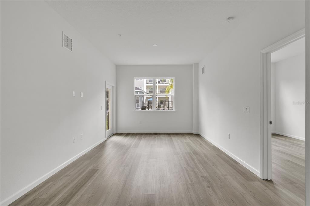 An empty room with light wood-look flooring, white walls, a window, and a doorway — 1230 SOUTHSTATION PLACE UNIT 105, ORLANDO, FL