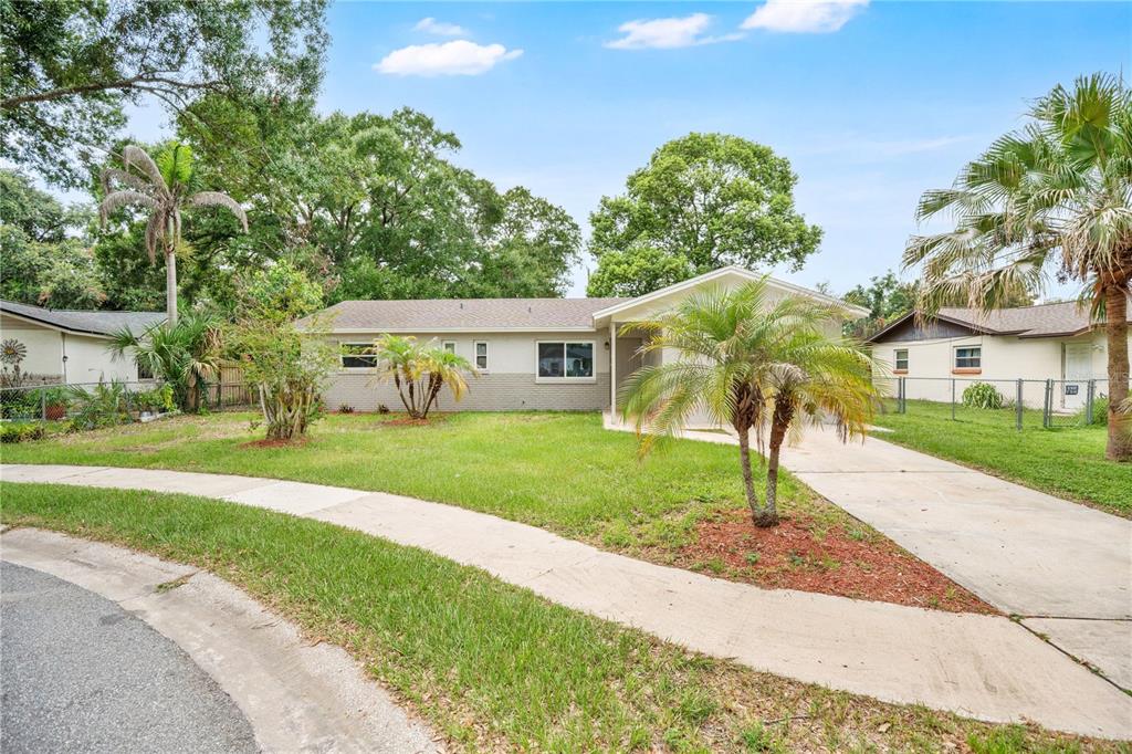 A single-story house with a gray brick exterior, a concrete driveway, and several palm trees — 130 KASEY DRIVE, ORLANDO, FL