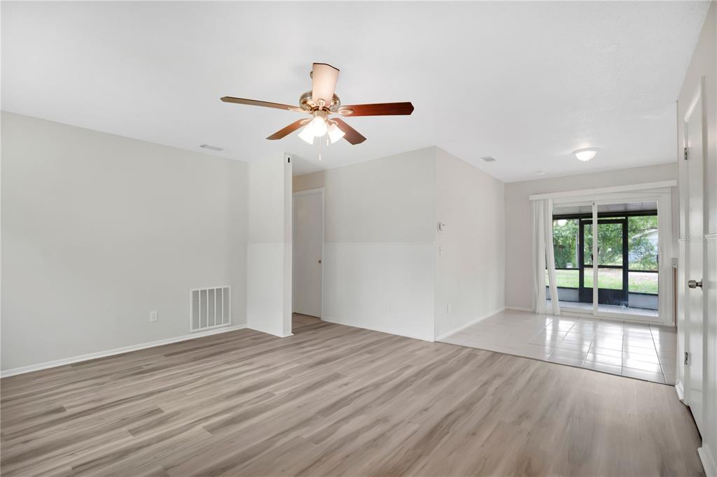 A living room with wood-look flooring, a ceiling fan, and a tiled dining area beyond — 130 KASEY DRIVE, ORLANDO, FL