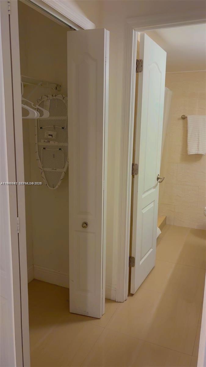 A view shows a closet with an ironing board and an adjacent bathroom door — 710 Washington Ave # 209, Miami Beach FL 33139, MIAMI BEACH, FL
