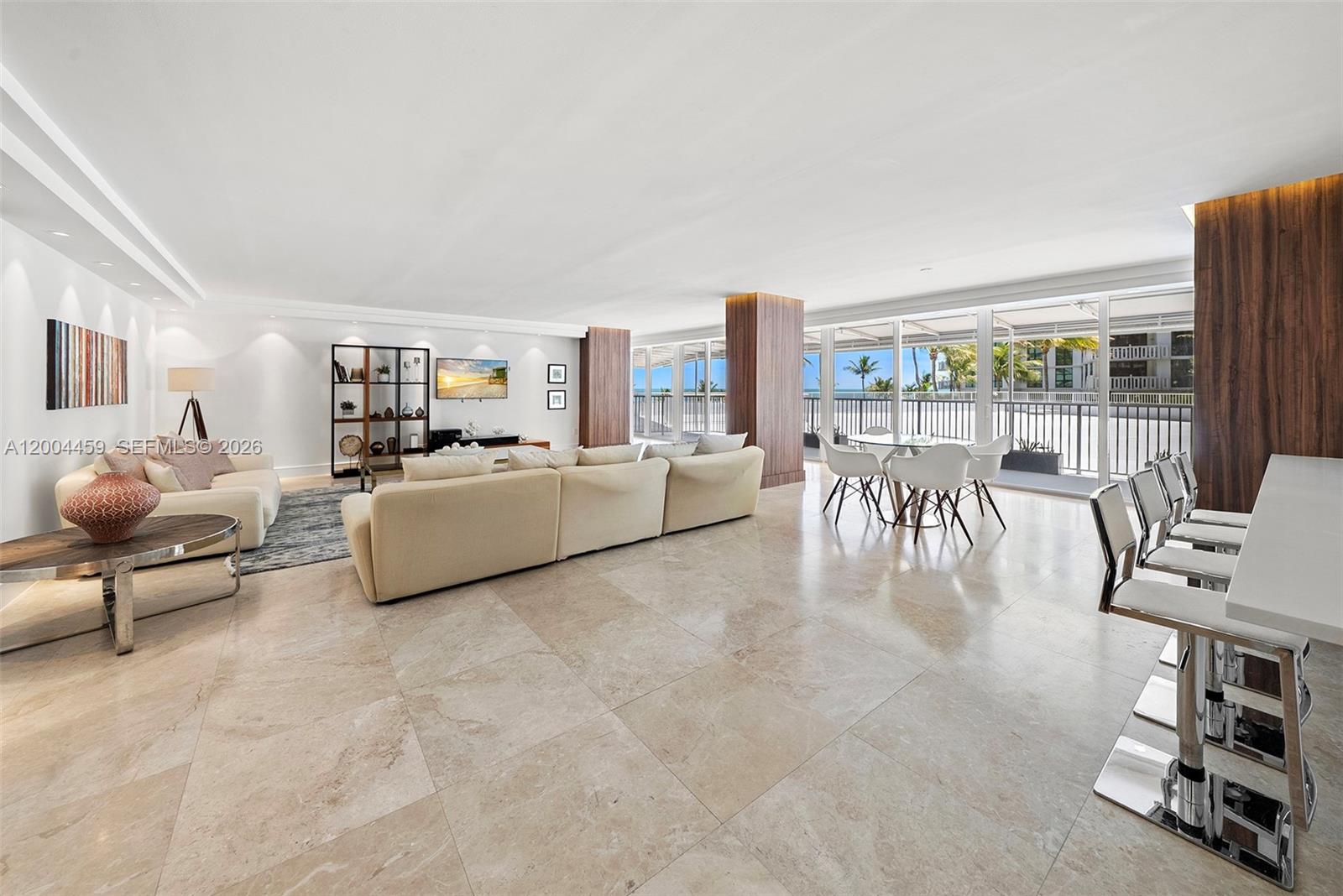 This open-concept living area features large tile flooring, a sectional sofa, and floor-to-ceiling windows — 600 Grapetree Dr, Key Biscayne FL 33149, KEY BISCAYNE, FL