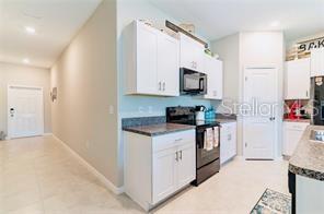 A kitchen features white cabinets, dark countertops, and stainless steel appliances — 5722 KEATON SPRINGS DRIVE, LAKELAND, FL