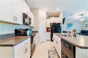 A kitchen features white cabinets, granite countertops, stainless steel appliances, and an open floor plan — 5722 KEATON SPRINGS DRIVE, LAKELAND, FL