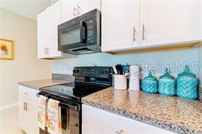 A kitchen features white cabinets, a black microwave, a black stove, and granite countertops — 5722 KEATON SPRINGS DRIVE, LAKELAND, FL