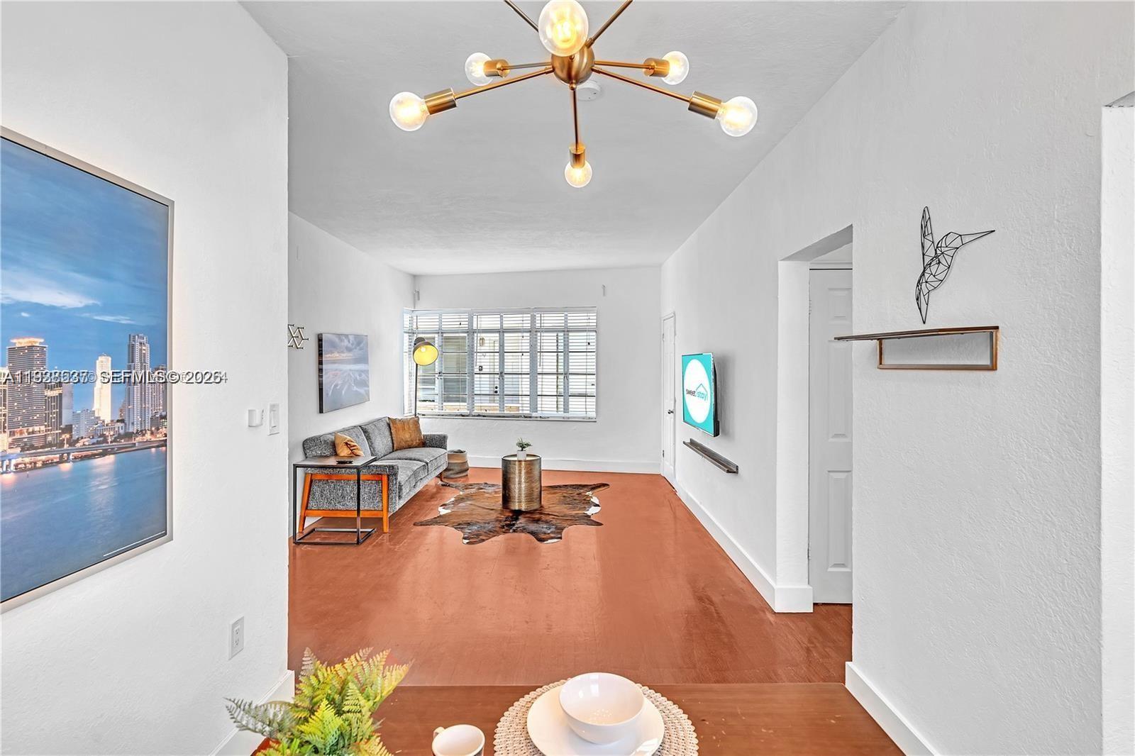 A living room features a modern chandelier, a gray sofa, and a cowhide rug — 3920 Garden Ave # 14, Miami Beach FL 33140, MIAMI BEACH, FL