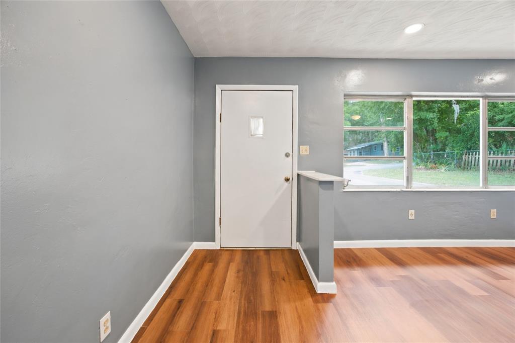A room with gray walls, wood-look flooring, a white entry door, and a half wall — 10920 SE 55TH AVENUE, BELLEVIEW, FL