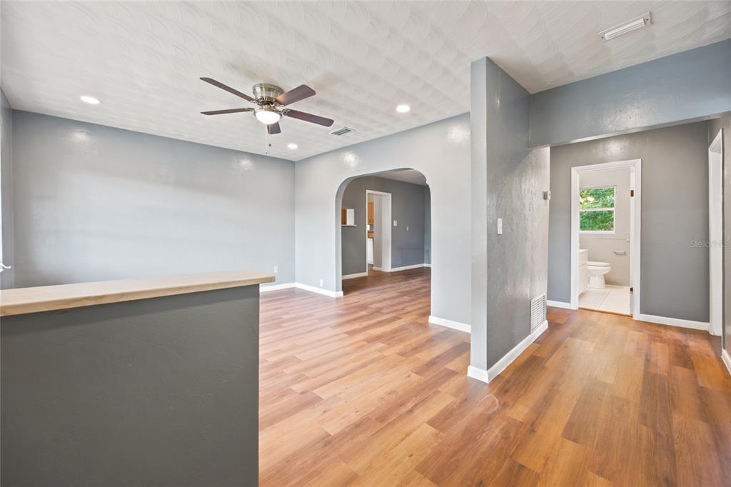An interior view shows a living area with wood-look flooring, gray walls, and an arched doorway — 10920 SE 55TH AVENUE, BELLEVIEW, FL