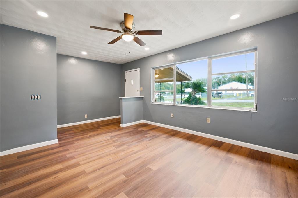 An empty room with gray walls, wood-look flooring, a ceiling fan, and large windows — 10920 SE 55TH AVENUE, BELLEVIEW, FL