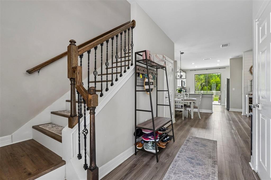 A staircase with wooden treads and metal balusters stands next to a metal entryway rack — 7673 YALE HARBOR DRIVE, WESLEY CHAPEL, FL