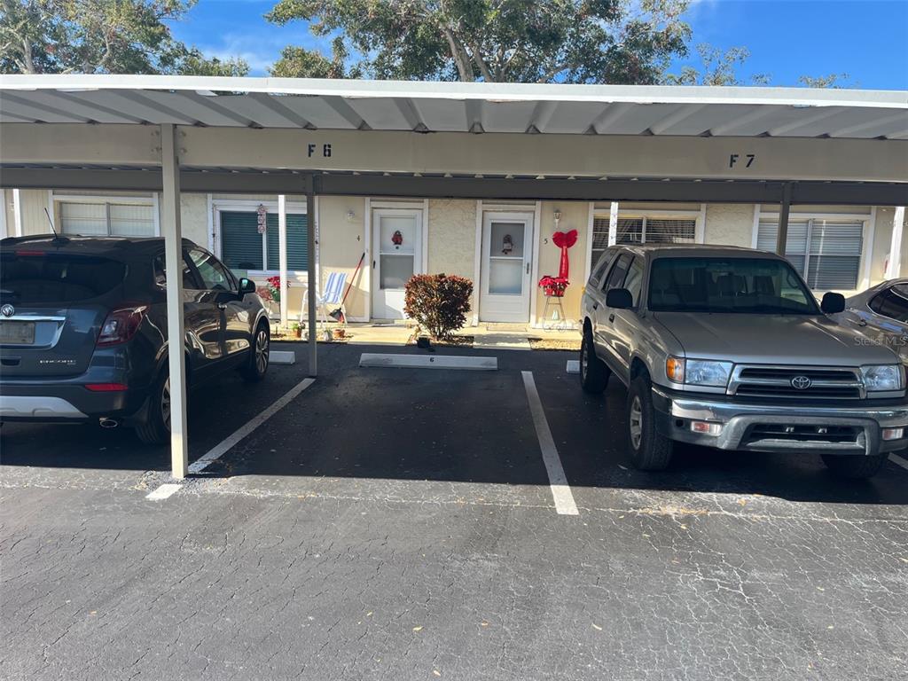 Two cars are parked under a covered carport in front of two residential unit doors — 670 GREEN VALLEY ROAD UNIT F5, PALM HARBOR, FL
