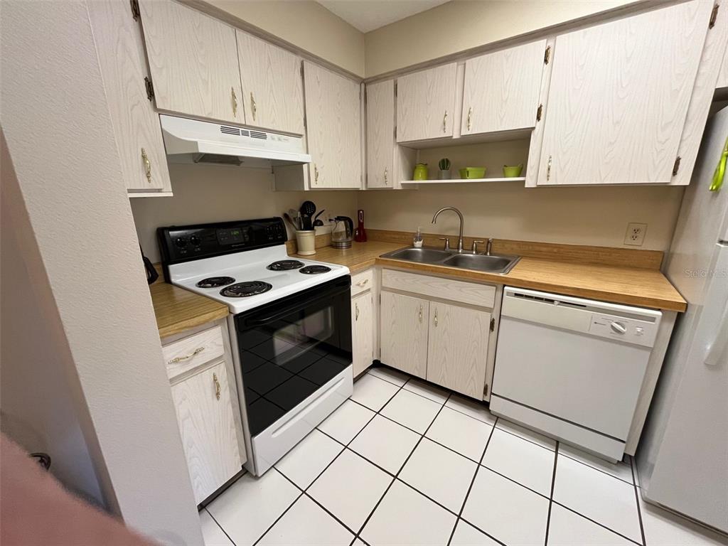 A kitchen features white cabinets, laminate countertops, a white stove, and a white dishwasher — 670 GREEN VALLEY ROAD UNIT F5, PALM HARBOR, FL