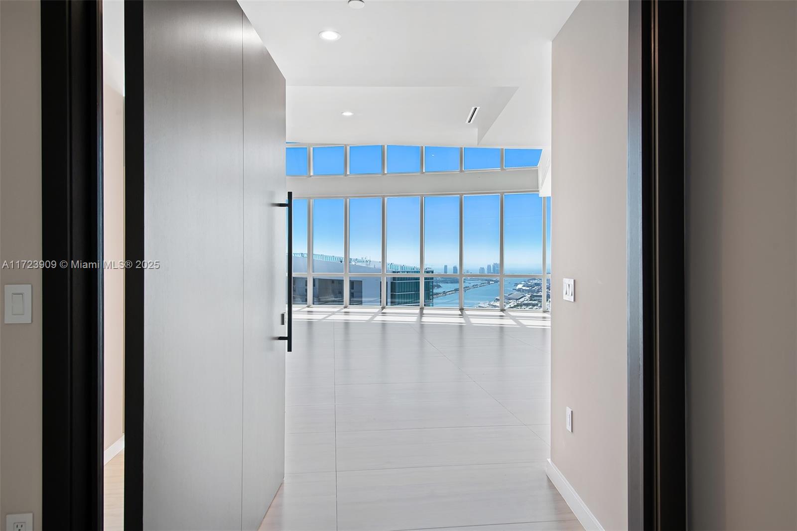 An open doorway reveals a bright, empty room with floor-to-ceiling windows overlooking the ocean — 851 NE 1st Ave # 5411, Miami FL 33132, MIAMI, FL