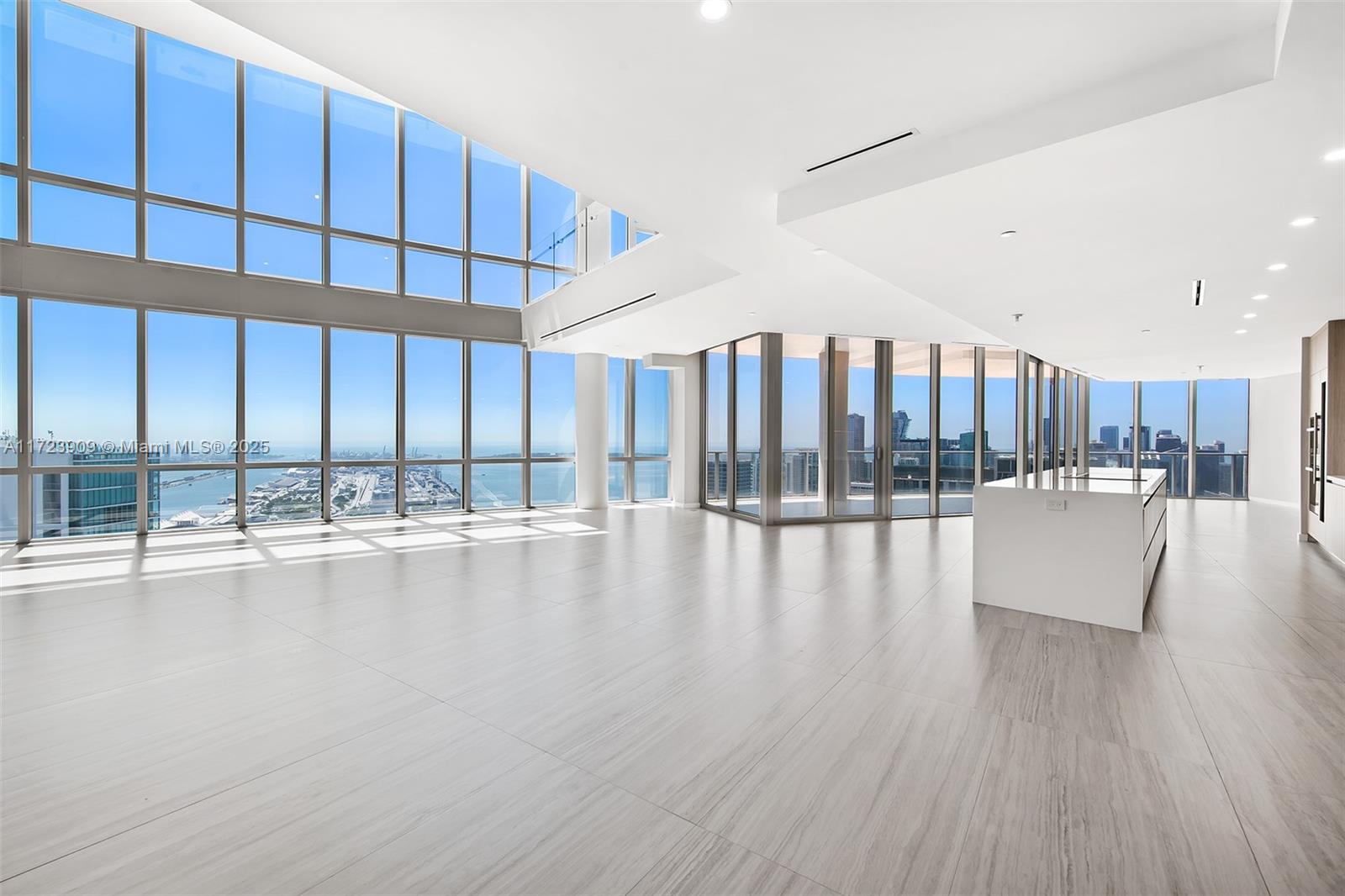 A modern, open-concept living space features floor-to-ceiling windows, light tile flooring, and a kitchen island — 851 NE 1st Ave # 5411, Miami FL 33132, MIAMI, FL