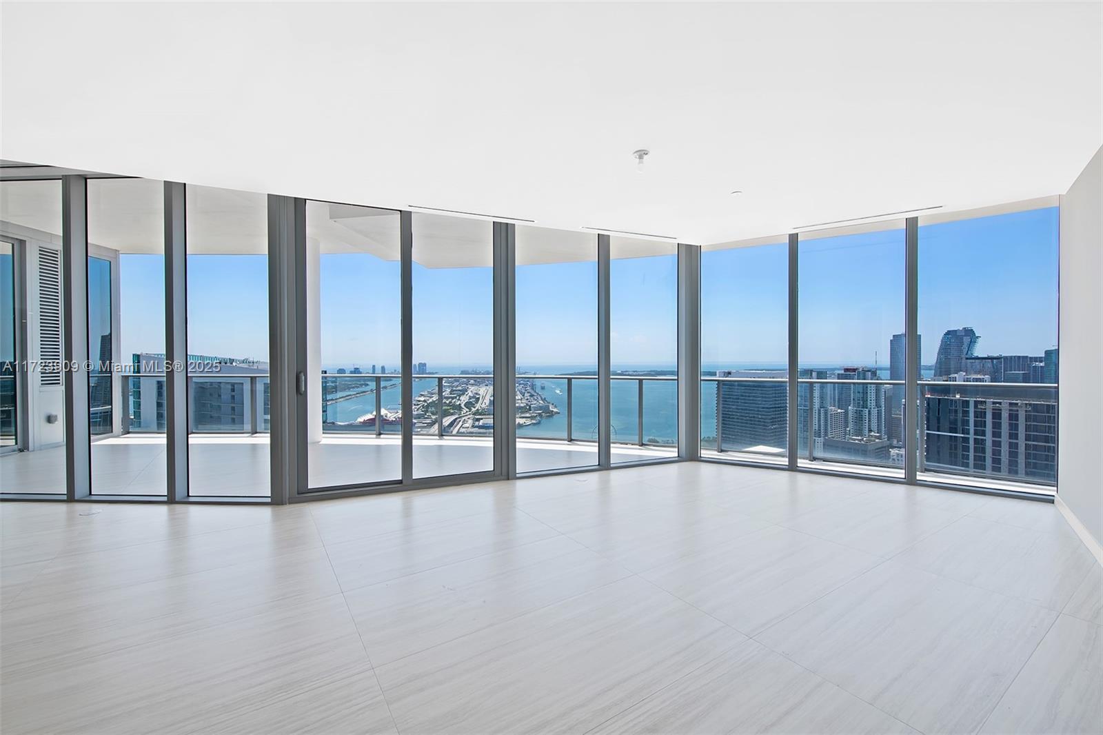 An empty room with light-colored tile floors and floor-to-ceiling windows overlooking a city skyline — 851 NE 1st Ave # 5411, Miami FL 33132, MIAMI, FL