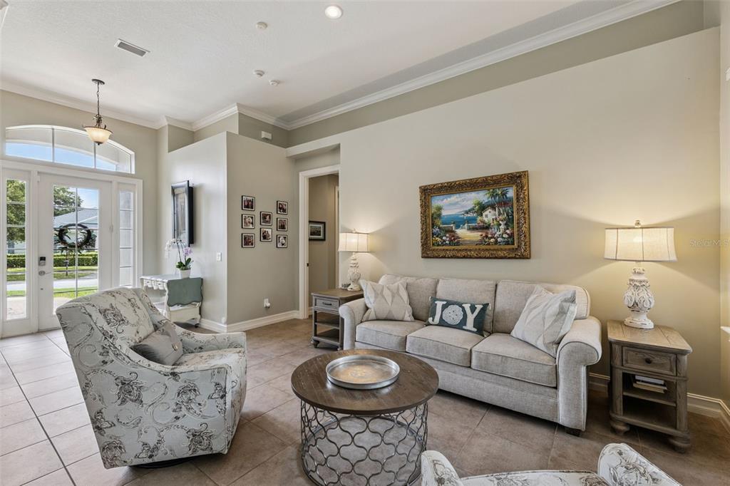 A living room features a sofa, patterned armchairs, a coffee table, and tiled flooring — 103 WISTERIA LANE, DELAND, FL
