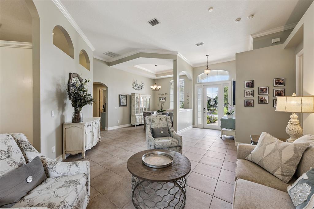 A bright living room features tile floors, neutral walls, arched niches, and a front entryway — 103 WISTERIA LANE, DELAND, FL