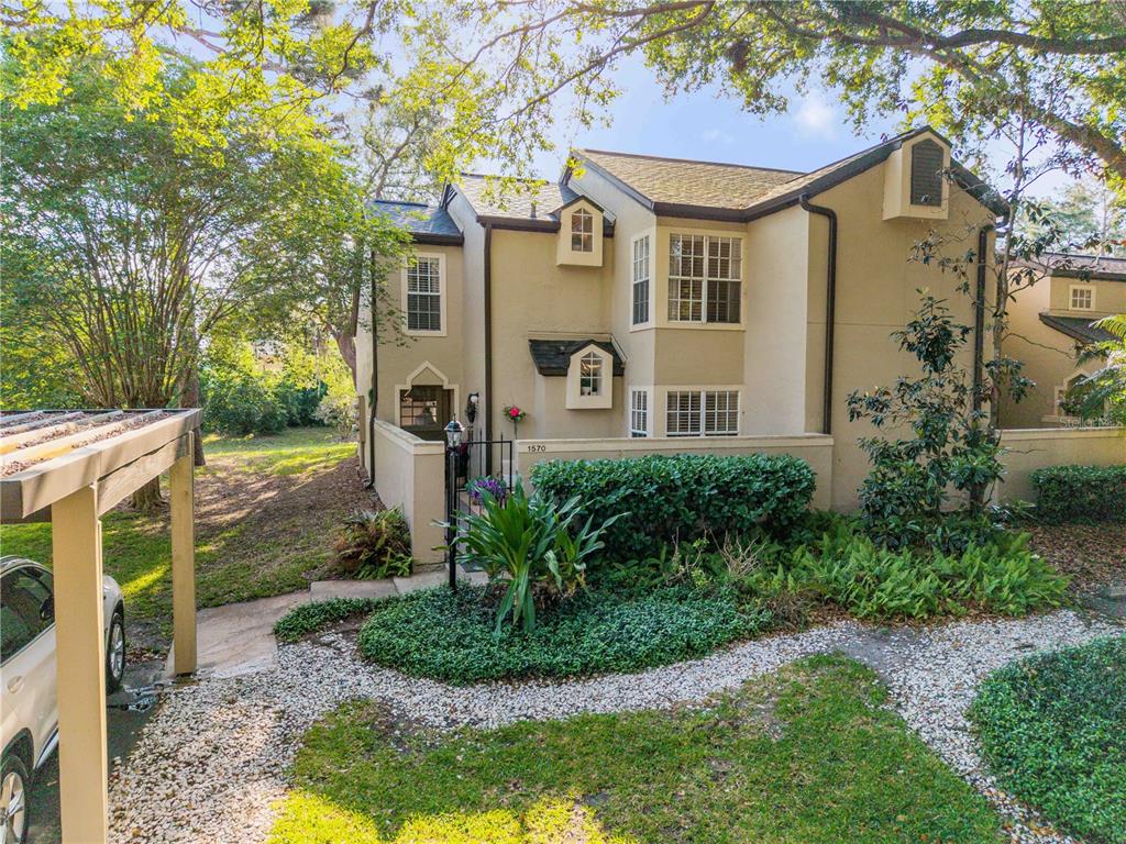 A two-story tan townhouse with a gated courtyard entrance and a covered parking structure — 1570 FARRINDON CIRCLE, LAKE MARY, FL