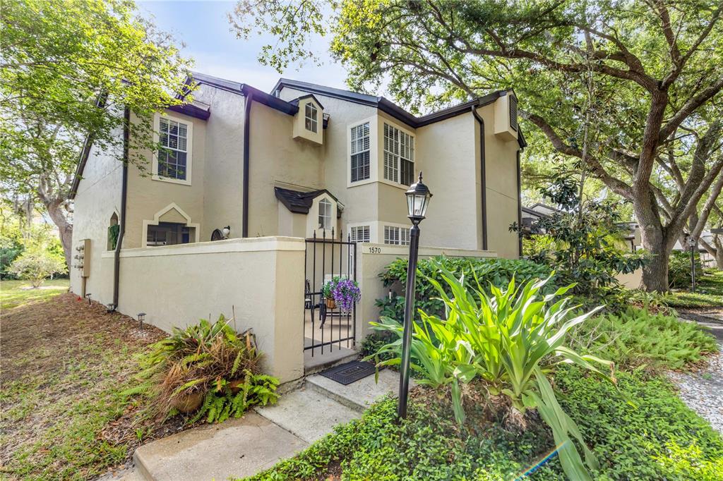 A two-story tan stucco townhouse features a gated front courtyard and mature shade trees — 1570 FARRINDON CIRCLE, LAKE MARY, FL