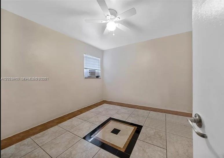 An empty room features light-colored walls, a ceiling fan, and tiled flooring with a decorative inlay — 1500 NW 69th Ter, Miami FL 33147, MIAMI, FL