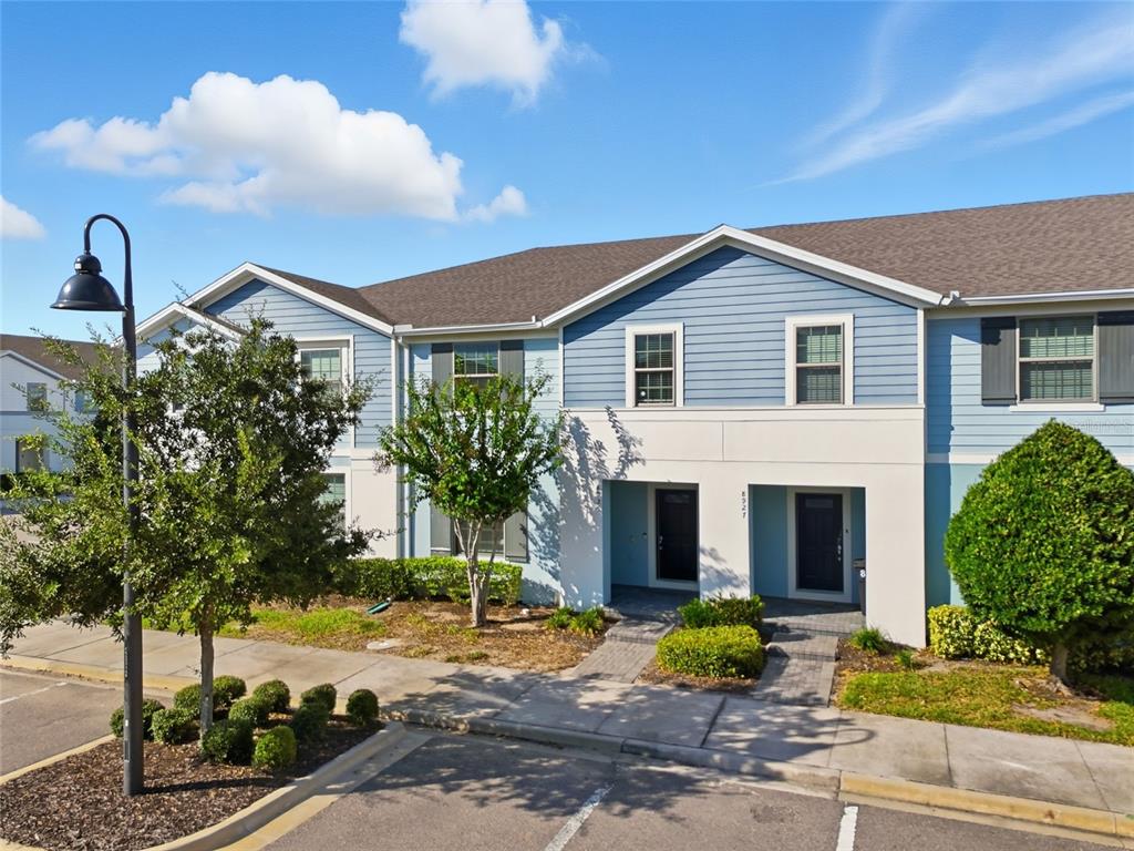 A two-story blue and white townhouse exterior with a paved walkway and landscaping — 8929 SYDNEY AVENUE, KISSIMMEE, FL