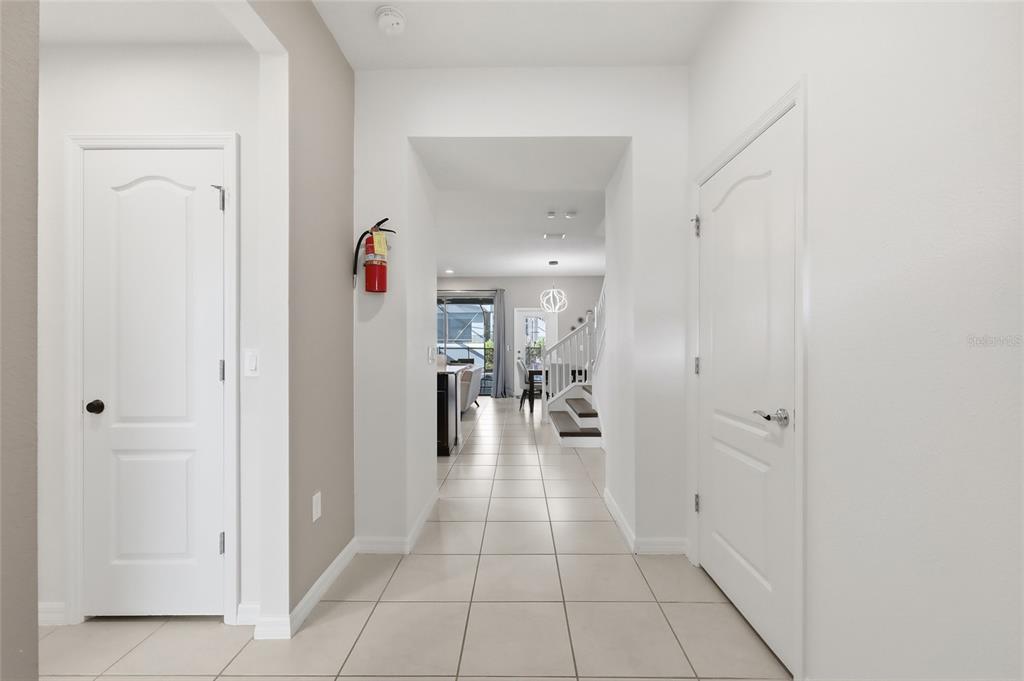 A tiled entryway leads to a hallway with a staircase and a view of the living area — 8929 SYDNEY AVENUE, KISSIMMEE, FL