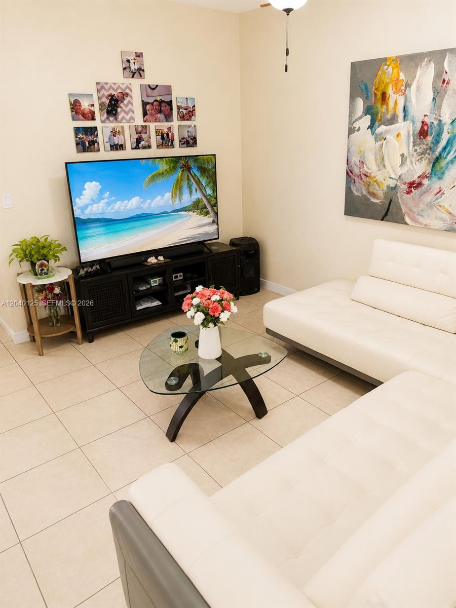 A living room features a white sofa, a glass coffee table, and a wall-mounted television — 12488 SW 122nd St, Miami FL 33186, MIAMI, FL