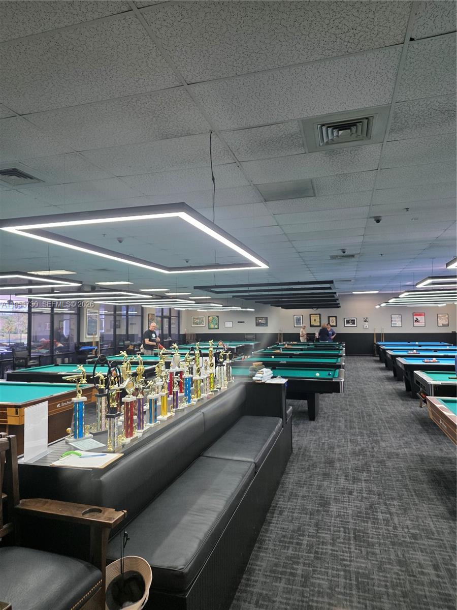 A large pool hall features multiple billiard tables, rows of trophies, and recessed ceiling lighting — 2612 Nassau Bnd # E2, Coconut Creek FL 33066, COCONUT CREEK, FL