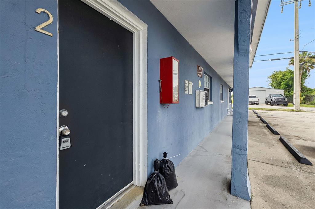 A blue exterior wall features a black door labeled number two and a red box — 601 STATE AVENUE UNIT 2, HOLLY HILL, FL