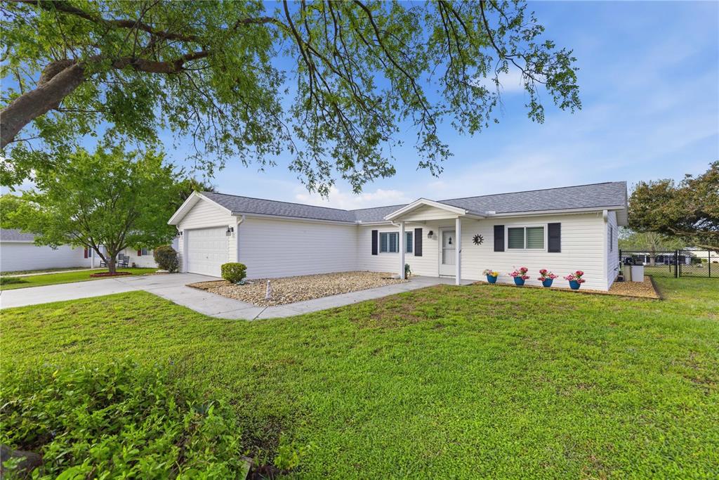 A single-story white house with a garage and a front lawn under a large tree — 17710 SE 105TH TERRACE, SUMMERFIELD, FL