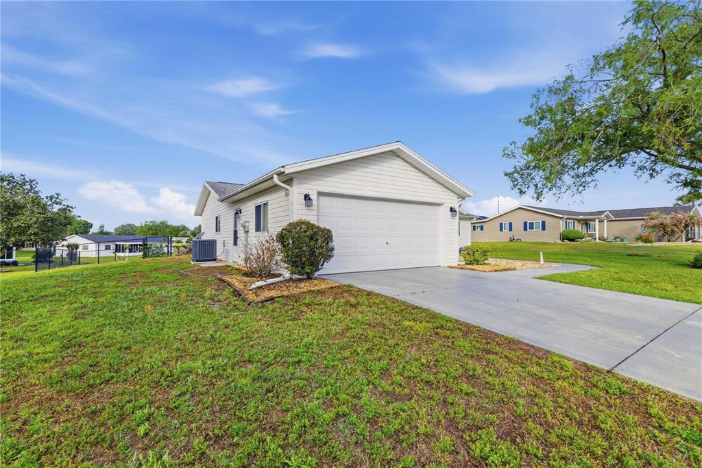 A white house with a garage and a concrete driveway sits on a grassy lot — 17710 SE 105TH TERRACE, SUMMERFIELD, FL