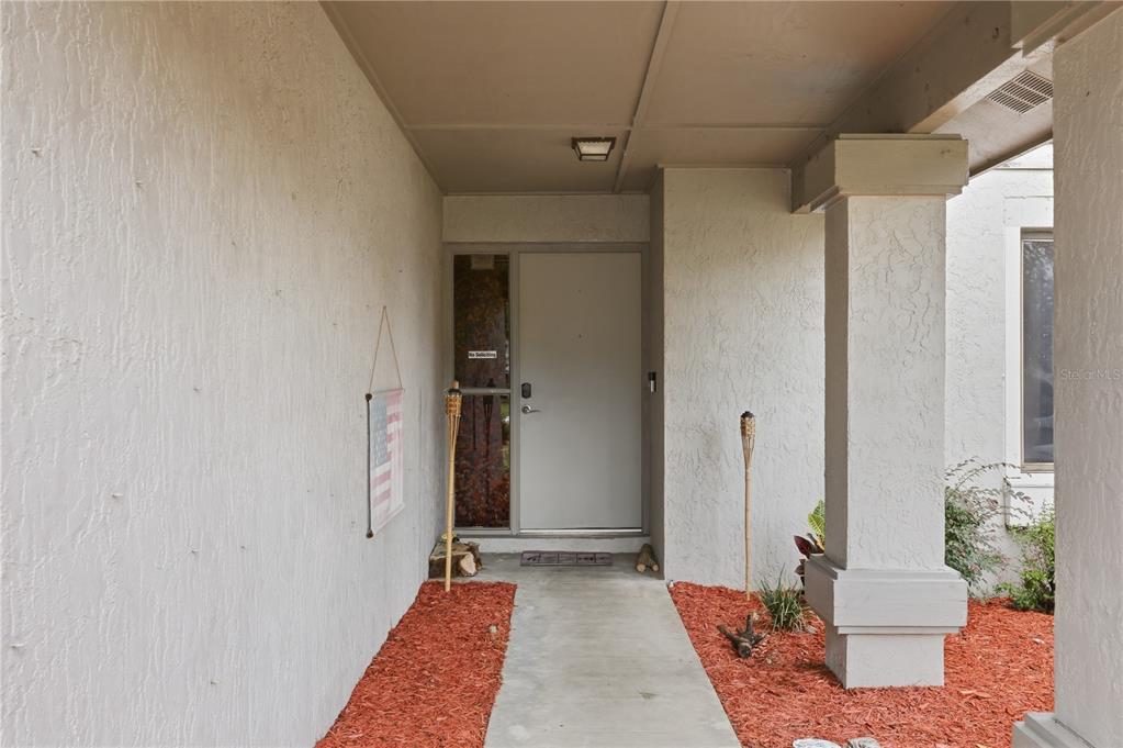 A covered concrete walkway leads to a front door with a side window and pillar — 5583 LONG LAKE DRIVE, ORLANDO, FL