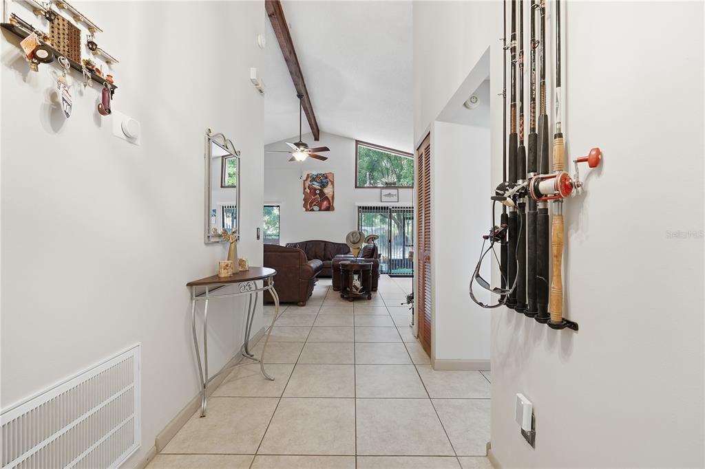 A tiled hallway leads to a living room with vaulted ceilings and a wooden beam — 5583 LONG LAKE DRIVE, ORLANDO, FL
