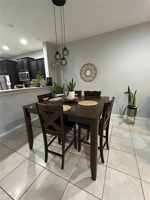 A dining area features a dark wood table with four chairs under a pendant light fixture — 10813 CORSICAN STREET UNIT 10, ORLANDO, FL