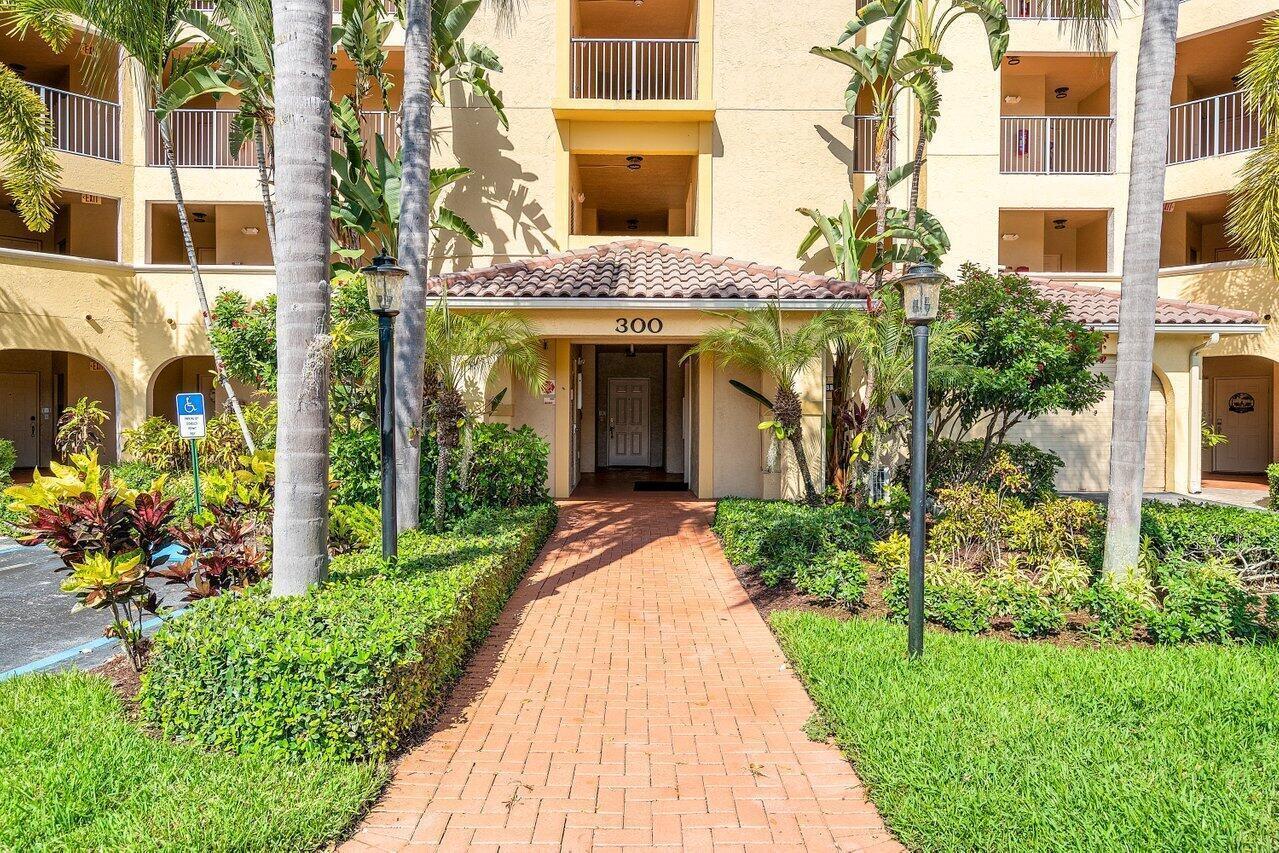 A brick walkway leads to the entrance of a multi-story apartment building labeled 300 — 300 Uno Lago Drive # 304, Juno Beach FL 33408, JUNO BEACH, FL