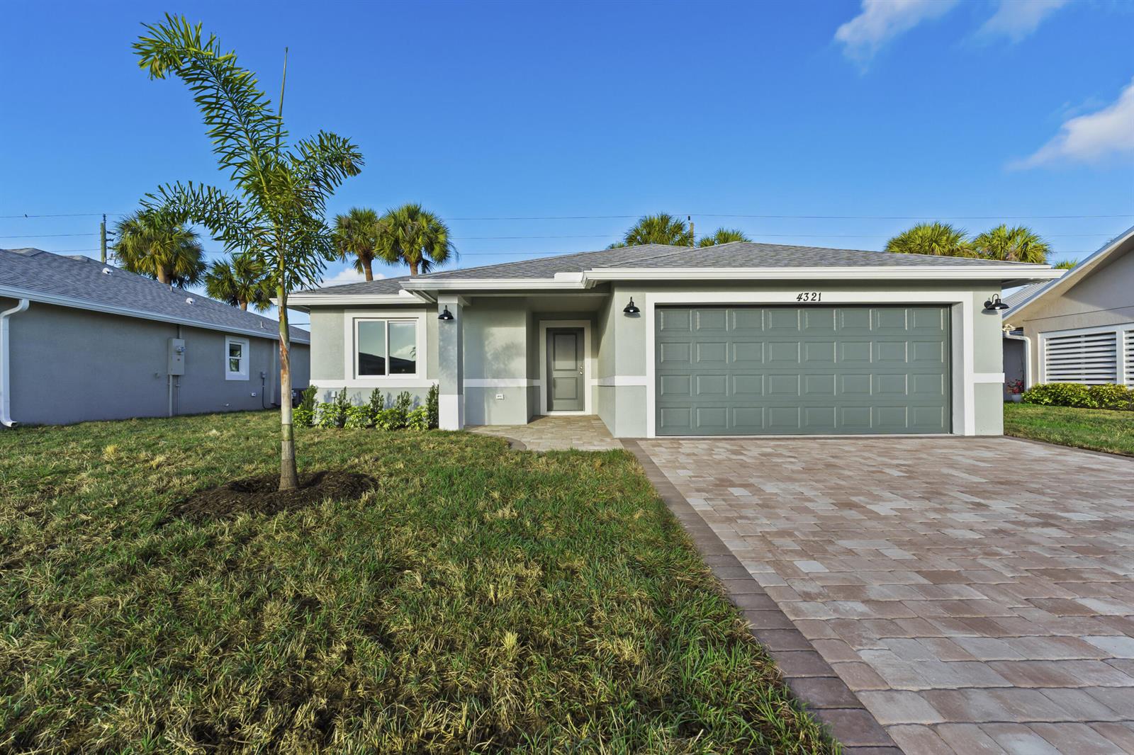 A single-story house with a gray garage, paved driveway, and a small palm tree — 4321 SW 15th Way, Okeechobee FL 34974, OKEECHOBEE, FL