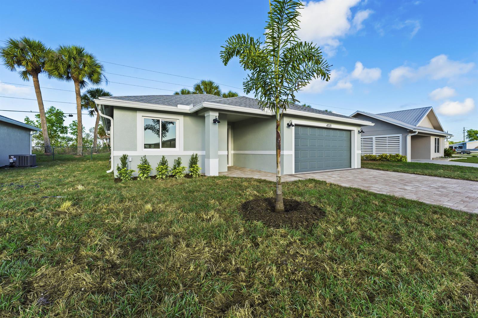 A single-story house with a gray garage, light green exterior, and a palm tree — 4321 SW 15th Way, Okeechobee FL 34974, OKEECHOBEE, FL