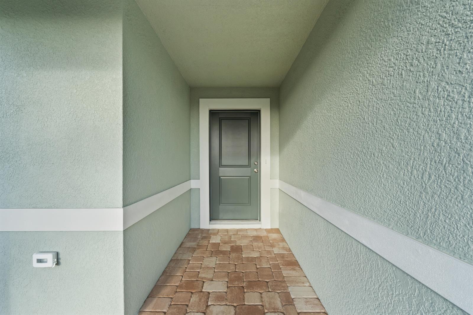 A covered entryway with light green stucco walls, white trim, and a paved brick floor — 4321 SW 15th Way, Okeechobee FL 34974, OKEECHOBEE, FL