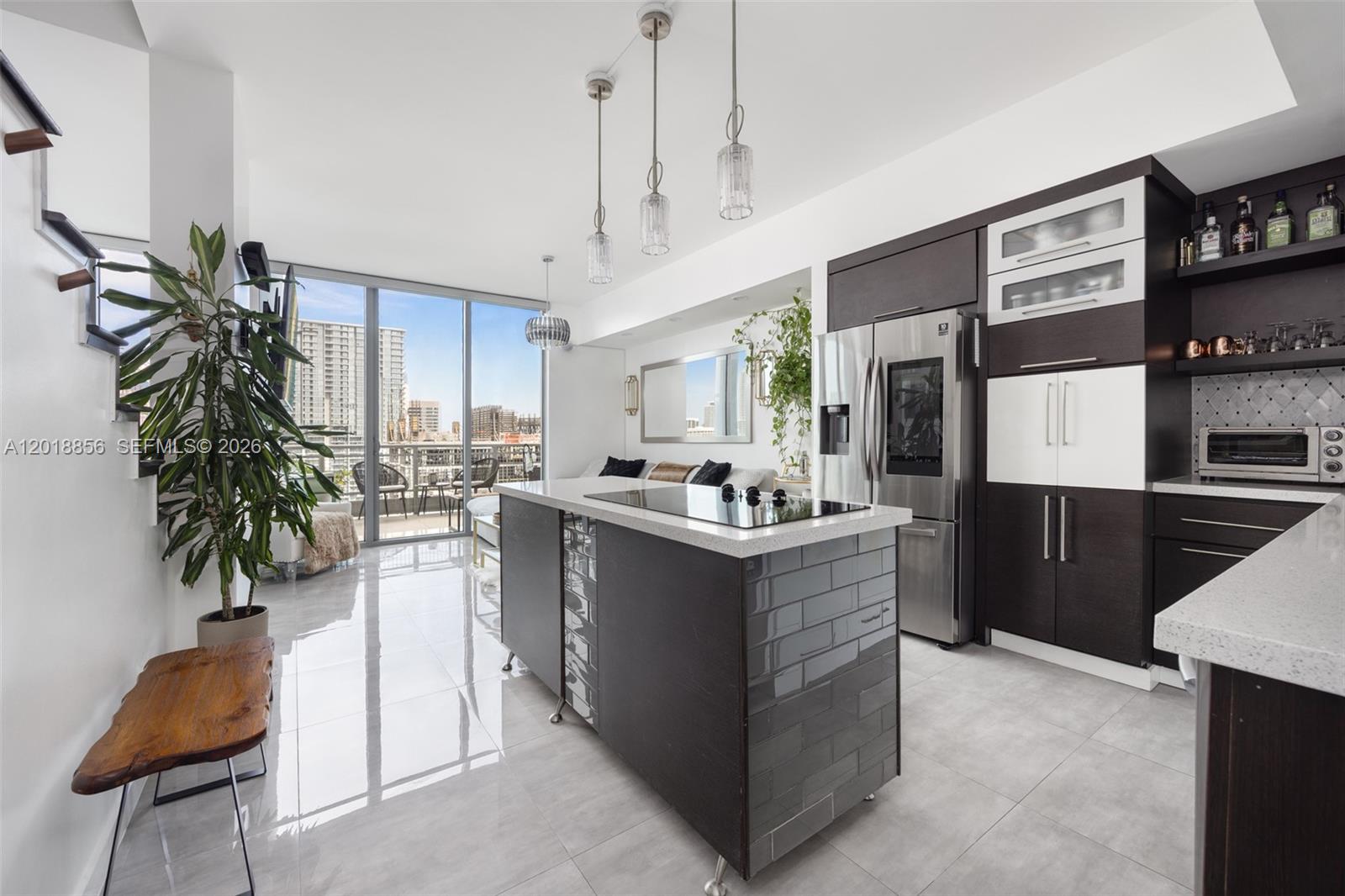 A modern kitchen features a tiled island, dark cabinetry, and floor-to-ceiling windows with city views — 690 SW 1st Ct, Miami FL 33130, MIAMI, FL